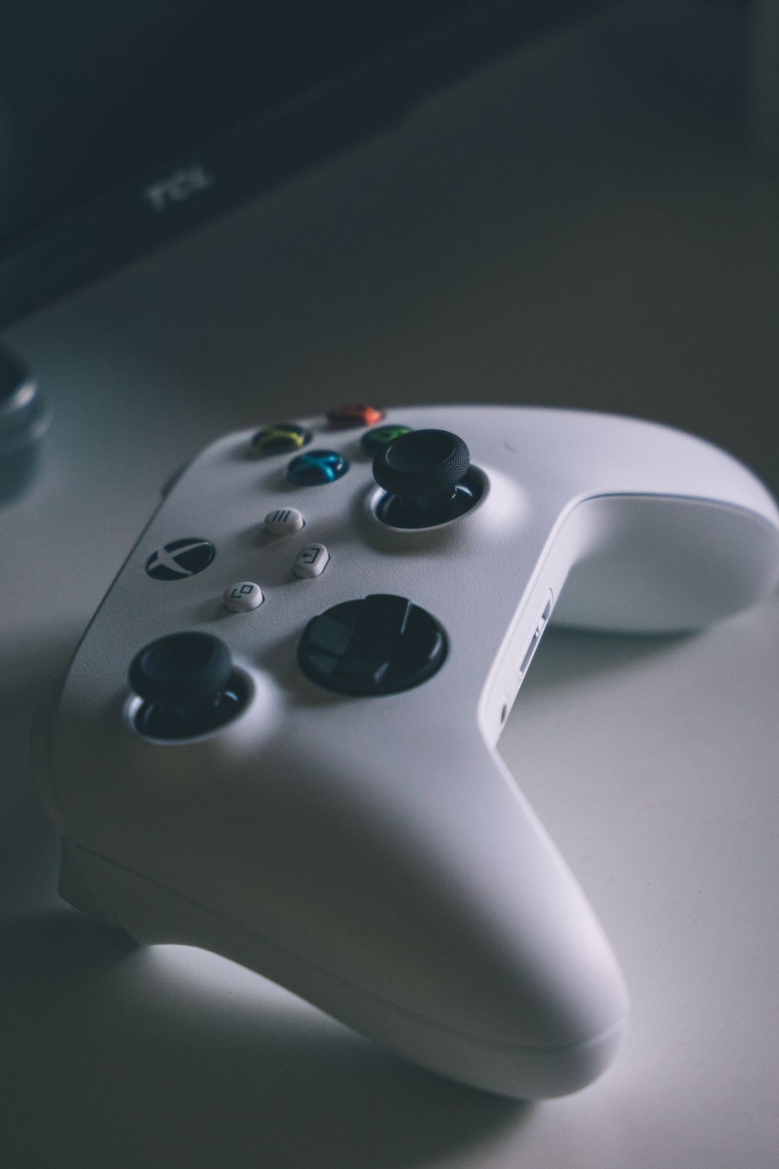A close-up of a white wireless game controller on a desk.